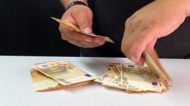Eller düzenli bir şekilde temiz, beyaz bir yüzey üzerinde değişen banknotlar halinde Avrupa banknotlarını sıralamak ve organize etmek, sabır ve sayımda hassasiyeti vurgulamak.