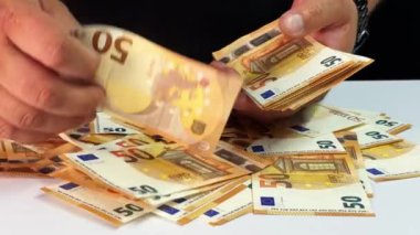 Bir kişi, her banknotun düzgünce düzenlendiğinden emin olmak için bir yığın Euro banknotunu dikkatlice ayırıyor. Konferansta para biriminin günlük ortamda ele alınması üzerinde duruluyor.