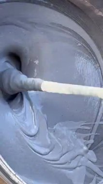 Bir işçi, kuvars duvar bileşimini bir kovada karıştırarak pürüzsüz ve düz bir doku sağlar. Hazırlık, çeşitli yüzeylerde etkili bir uygulama için çok önemlidir..