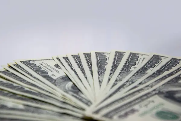 Beyaz bir yüzeye yayılmış yüz dolarlık banknotların yakın plan fotoğrafı..