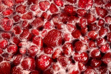 Çilek reçeli kaynama sürecinde ilerleme kaydediyor. Ev yapımı çilek reçeli yapma süreci. Kırmızı tatlı şurup ocakta kaynıyor..