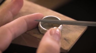 Yaklaş, kuyumcu elleri, ahşap aletler kullanarak gümüş yüzük yapan kuyumcular. El yapımı üretim, mücevher, el yapımı iş. Mücevher ustası el yapımı. Gümüş yüzük parlatıcısı.
