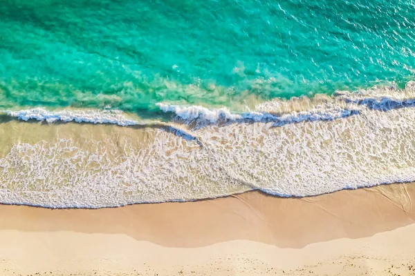 Beach top view with wave foam. Seashore sand and amazing sea. Wallpaper background. Top view beach sea. Wave roll into beach with white clean foam. Footprints on the beach sand.