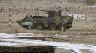Armored personnel carrier at training ground performs exercises to pass obstacles. Armored personnel carrier with a gun. Real war between Ukraine and Russia. Military equipment at training ground.