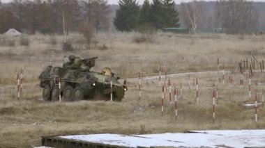 Soldiers march in the background. Military exercises in winter. Armored personnel carrier in a military town. Armored wheeled vehicles on exercises in Ukraine.Armored vehicle intelligence.