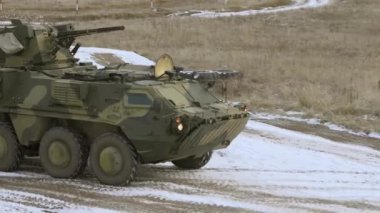 Close-up of an armored personnel carrier of the Ukrainian army riding on the road. Armored personnel carrier with a machine gun. Military exercises in winter. Ukrainian military equipment.