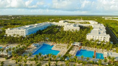 Otel binalarının havadan görünüşü, temiz su, yeşil palmiye ağaçları olan yüzme havuzları. İnsansız lüks bir tatil köyü. Boş şezlong, havuz ve plaj. Turizm sektöründe kriz. Otelde turist yok..