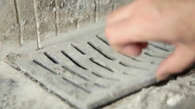 Mans hand opens the grate of the fireplace. Cleaning the fireplace and grate from ash and dust. Cleaning the fireplace and preparing for the heating season