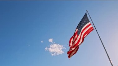 Güneşli bir günde açık mavi gökyüzüne karşı rüzgarda dalgalanan bir bayrak direğinde Amerikan bayrağı. Yakından, alttan, 4K. Amerika Birleşik Devletleri 'nde Amerikan Bayrağı Dalgalanması Bağımsızlığı Gösteriyor.