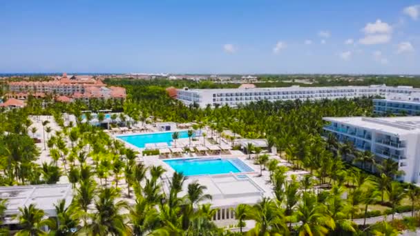 奢华的度假胜地酒店周围有海岸 游泳池和绿色棕榈树 风景与现代酒店在海上 蓝色的水 建筑物 — 图库视频影像