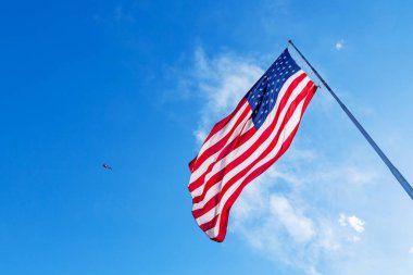 Rüzgarda dalgalanan Amerikan Bayrağı mavi bir arka planda. Amerikan Bayrağı. Mavi gökyüzünün önünde Amerika Birleşik Devletleri 'nin ünlü bayrağını sallıyordu. Bağımsızlık Günü. Seçim Günü