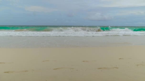 新鲜的海浪在多云的天气里冲向一个美丽的沙滩 前方有脚印 暴风雨前天空乌云密布 海洋里的暴风雨天气 海洋和天空背景景观 — 图库视频影像
