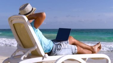 Yazar okyanustan esinlenilmiş bir kitap yazar. Seyahat ilhamı. Sahilde yazar. Genç adam okyanustaki dalgalara bakan bir dizüstü bilgisayarda yazıyor. Tropikal bir tatilde serbest çalışan. Serbest ve uzak çalışma