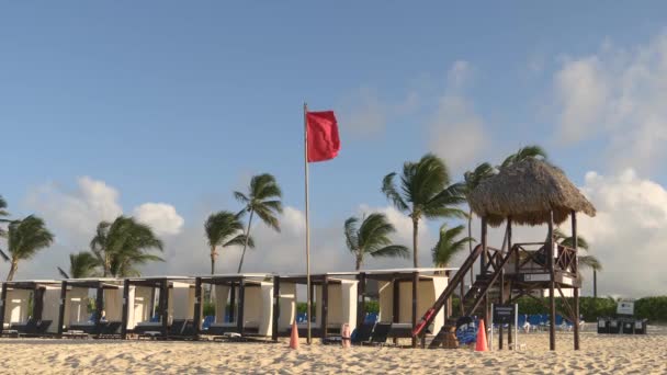 ドミニカ共和国 2021年5月 赤い旗がビーチのライフガードスタンドの上に風に乗って飛びます 荒天時には空のビーチ ライフガードはビーチと海を見ている 赤旗水閉鎖 — ストック動画