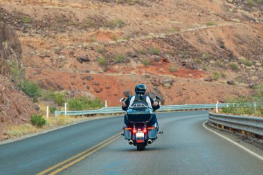 Amerika 'da motosiklet gezisi. Birkaç motorcu otoban boyunca kayaların arka planına ve dikiz aynasına doğru gidiyor. Motosikletli tanınmayan motorcular.