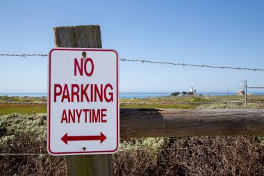Dikenli tellerle çitlerde park yeri yok. Arka planda okyanus manzaralı deniz feneri olan park yeri yok. Amerika 'da turist yolunda park yeri yok.