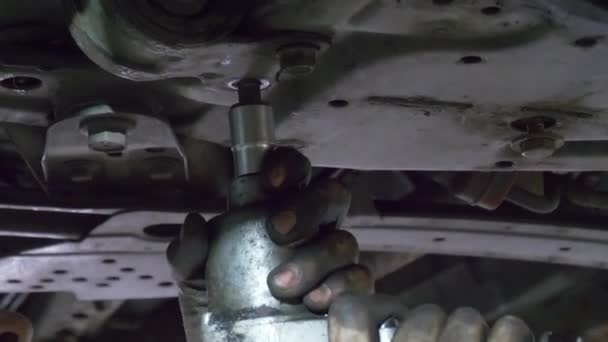 关闭螺丝钉汽车螺栓 汽车机修工的脏手把车底的螺栓弄脏了 特写镜头 汽车起落架的机械螺杆 汽车悬架修理 — 图库视频影像