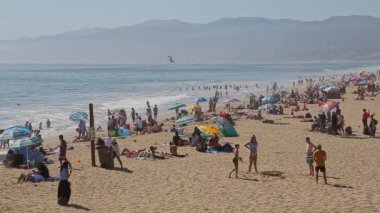 Santa Monica, Kaliforniya, ABD - 8 Mayıs 2017 - Plaj halkı deniz yolculuğunu çok kalabalık karşıladı. Plajda bir sürü yolcu var. Pasifik Okyanusu kıyısında Santa Monica Sahili 'nde insanlar okyanusun kenarında dinleniyor.