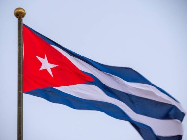 Bayrak direğinde dalgalanan Küba bayrağı. Rüzgarda dalgalanan Küba bayrağı. Rüzgarda dalgalanan Küba bayrağına yakın plan temiz bir gökyüzü. Küba bayrağı Dramatik görünüm, alt görünüm