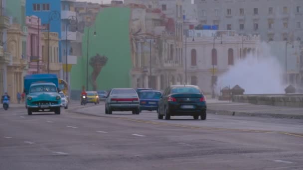 バックグラウンドで海でマレコンを運転するヴィンテージカー 冬の嵐の間 ハバナ キューバのマレコンで波が交差する 路上で走る車で海に近い街の景色 — ストック動画