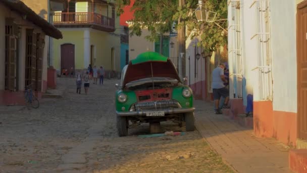 老式经典的美国汽车在街上修理 修理工作用的是一辆美国旧车的发动机 一辆旧的美国汽车正在镇上的街道上修理 古巴的神圣生活 Trinidad Cuba Jan 2022 — 图库视频影像