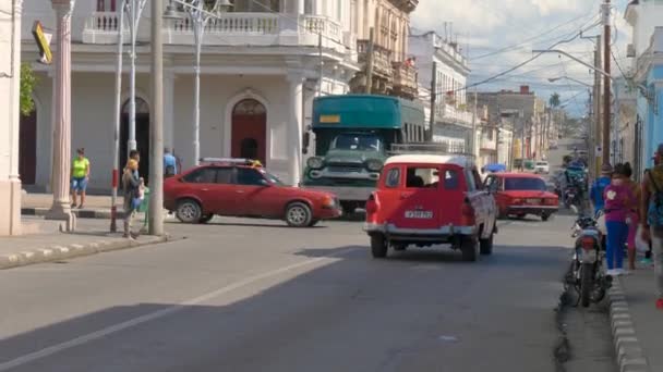 メインストリートで運転する古典的なアメリカ車 メキシコの路上で交通と都市生活が激しくなった 地元の人や観光客は キューバ キューバ Jan 2022の通りや歩道を歩いています — ストック動画
