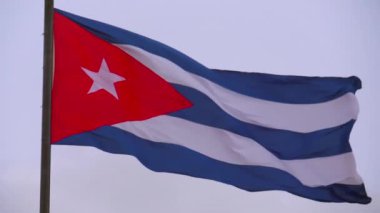KUBA FLAG. Küba bayrağı bulutlu bir arka planla rüzgarda dalgalanıyor. Bulutlu gökyüzünün önünde Küba 'nın ünlü bayrağını sallıyor. Havana 'nın merkezinde büyük Küba bayrağı rüzgarda dalgalanıyor.