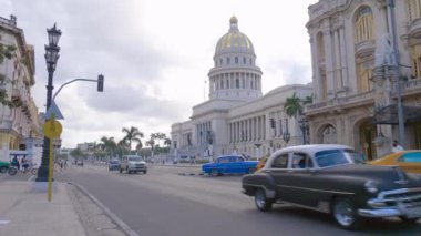 Havana, Küba - 10 Ocak 2022 - Renkli Klasik 50 'ler Amerikan Klasik Küba arabaları sokakta sürüyor. Küba 'daki eski Havana' daki Ulusal Meclis Binası. Habana 'da Retro Vintage arabalar