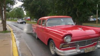 1957 Ford Custom Tudor Sedan 312 Thunderbird Special. Antika kırmızı retro arabalar yağmurlu bir günde Küba tatil köyünün merkez caddesi boyunca sürüyorlar. Kırmızı bir vintage taksinin yakın çekimi. Varadero, Küba - 14 Ocak 2022