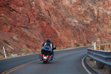 Amerika 'da motosiklet gezisi. Birkaç motorcu otoban boyunca kayaların arka planına ve dikiz aynasına doğru gidiyor. Motosikletli tanınmayan motorcular.