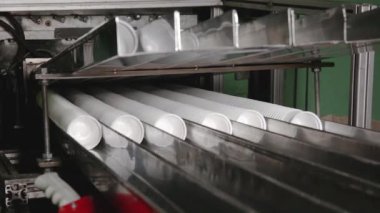 Plastik kaplar termoform işlemi. Plastik bardaklar üretim tesisi, tek kullanımlık gıda paketi donanım üretim hattı. Yüksek performanslı otomatikleştirilmiş makineler üzerinde çalış. Taşıyıcı banttaki plastik bardaklar.