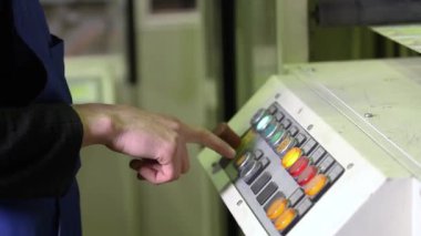 İşçi otomatik makineyi çalıştırmak için düğmeye basar. Düğmeye basılıyor ve otomatik sanayi hattı başlatılıyor. Üretim Fabrikası. Otomatik Sanayi Hattı Kullanımı Taşıyıcısı. Endüstriyel kontrol paneli