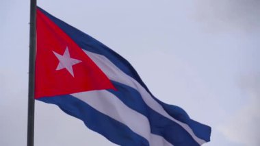 Bulutlu bir günde rüzgarda dalgalanan bir bayrak direğinin üzerindeki CUBAN bayrağı. Yakın çekim, alt manzara, Havana 'da Küba Bayrağı Dalgalanması Küba' nın Bağımsızlığını Gösteriyor. Doğal tekstil Küba bayrağı dalgalanıyor.