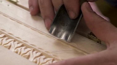 Tahta oyma. Ahşap oyma ustasının elinde çiçek desenleri ve süslemeleri tahta bir kutuya takmak için kesme aleti var. Hobi olarak el işi kavramı, yetenek, yetenek ve zarif sanat eserleri..