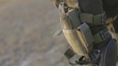 Tabanca kılıfında silahlı bir adamın kemeri var. Asker silahını çıkarır ve kılıfına bir tabanca yerleştirir. Tabanca kılıfında, bir askerin bacağında. Yaklaş. Askeri bir kavram. Silahlı kuvvetler ekipmanı.