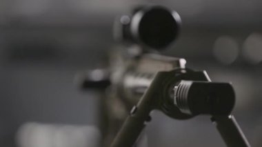 Bulanık arka planda dürbünlü keskin nişancı tüfeği, yakın çekim, sığ alan derinliğinde stüdyo atışı. Keskin nişancı saldırı tüfeğinin detaylı makro görüntüsü. Namludan keskin nişancı tüfeğine odaklan. Silah ticareti.