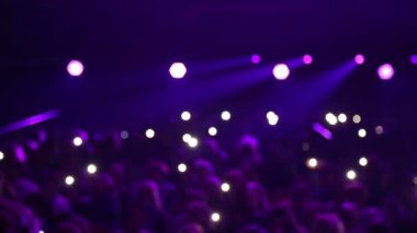 Seyirci ile konser salonu. Ufuk seyirci salonda ışıklar karanlıkta oturuyor. Bulanık arka plan: tezahürat izleyiciyle Bokeh aydınlatma kapalı konserinde eller yukarı.