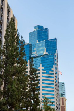 Modern şehir silueti sıcak günbatımı ışığı altında parlar. Günbatımının altın rengi modern ufuk çizgisinin cam camlarından yansıyor. Gökdelenler modern gökdelenleri tanımlar, günün son ışığında yıkanırlar..