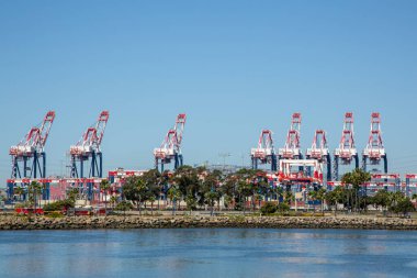 Nakliye vinçleri ve liman altyapısı. Limanda vinçleri olan itfaiye araçları. Büyük endüstriyel vinçler işlek bir nakliye limanında dik dururlar. Liman siluetine hükmeden büyük turnalar berrak bir gökyüzünün altında.