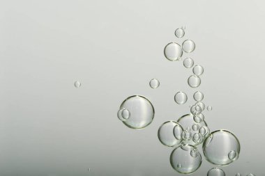 Su kabarcıkları hafif bir arkaplandan aşağı düşüyor.