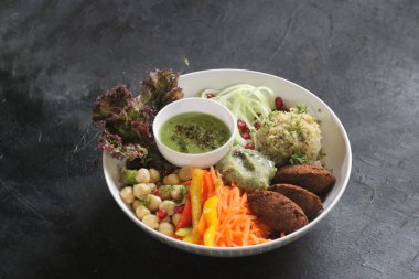 Lübnan Falafel kasesi, yanında nohut, salatalık, biber ve havuç. Kırsal bir arka planda büyük bir kasede şekillendirilmiş.