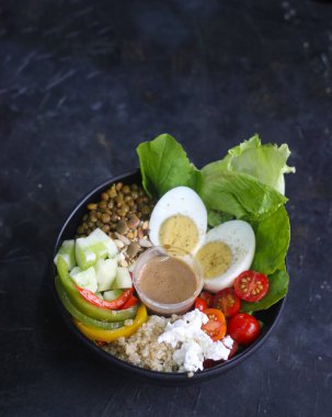Yanında fasulye, mısır, at gramı ve naneli zeytin sosu gibi taze sebzeli yumurta salatası. Beyaz kasede servis edilen protein salatası.