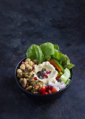 Humus nohutlu Lübnan salatası taze sebzeler ve yeşilliklerle servis edilir, zeytin ve nar ile süslenir..
