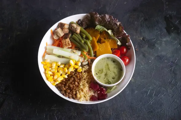 stock image Buddha wholesome bowl with fresh vegetables such as beans, corn, horse gram and vegan dressing on the side.