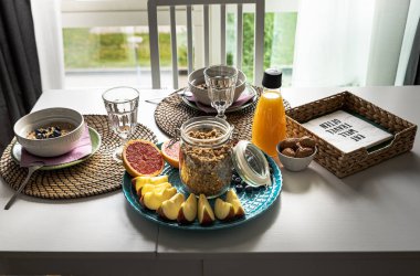 Lezzetli yulaf lapası, elma dilimleri, greyfurt, fındık ve portakal suyunu beyaz ahşap bir masada iç mekanda sağlıklı bir kahvaltı. Sıcak bir evde güneşli bir pencerenin yanında iki ya da iki kişilik sade bir yemek.