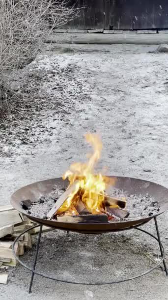 雪が冬に降っているので 火鉢や暖炉での火災は その年の最も寒い月の間に暖かさと居心地を伝えます 雪片が天から降ってくるときの火のついたボウルの閉まりは 居心地や大きさを伝えます — ストック動画