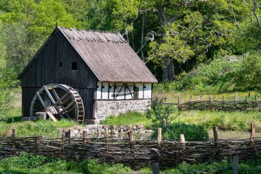 Countryside thatched house with wooden mill surrounded by green vegetation, trees and lush nature. Wooden or half timbered farmer factory in a meadow conveys bio farm products or natural food. Gamla Lundavgen, Blentarp, Sweden