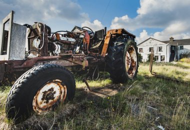 Paslı motor ve mekanik parçalar olarak eksik vücut parçalarına sahip eski traktör görülebilir. Terk edilmiş tarım aracı, tarım ve kırsal nüfusun azalmasını iletiyor. Yamyamlaşmış traktör - inisheer Aran Adaları, Galway İlçesi, İrlanda