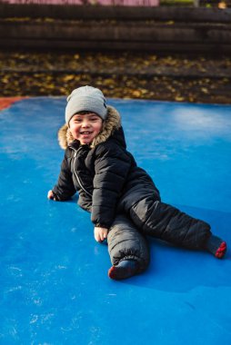 Alçak, gülümseyen bir çocuk mavi şişme bir trambolinde oturuyor. Yorgun bakışlı bir çocuk bir hava fedaisine gülüyor. Zıplayan bir zeminde yatan yorgun ve mutlu yüzlü bir çocuk.