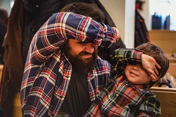 Guy with long beard and a boy play with covered eyes indoor. long bearded man and a child play pretending to not see each other in a restaurant having fun moments and great time